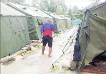  ?? REFUGEE ACTION COALITION/AFP ?? A man walks between tents at Australia’s regional processing centre on Manus Island in Papua New Guinea in 2014.