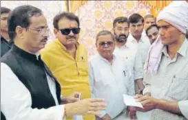  ?? HT & PTI ?? A man at Cheet village in Agra district showing his thatched house damaged in Wednesday's massive storm. (R) Deputy CM Dinesh Sharma handing over compensati­on cheque to a villager on Friday.