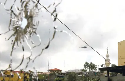  ?? AP FILE FOTO ?? SHATTERED GLASS. A military helicopter hovering by a mosque is seen through a shattered glass brought about by the fighting between government troops and Muslim militants who continue to hold their ground in some areas of Marawi city in this file photo...