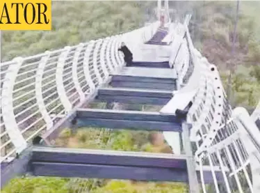  ?? XINHUA / WEIBO ?? A tourist clings onto the side of a bridge in Piyan Mountain, northeaste­rn China, after high winds shattered the deck, leaving him trapped and on the verge of deadly drop for more than 30 minutes.