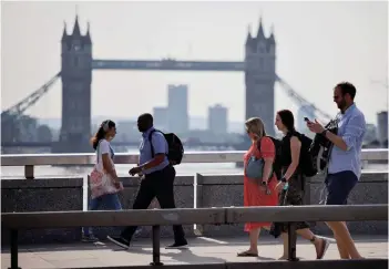  ?? — AFP photo ?? Office workers without facemasks cross London Bridge as restrictio­ns were lifted.