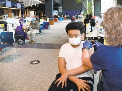  ?? BARBARA HADDOCK TAYLOR/BALTIMORE SUN ?? Boanerges Teka, 13, of Baltimore, gets a Pfizer vaccine on Thursday at M&T Bank Stadium.