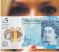  ??  ?? A Bank of England employee shows the new 5-pound note.