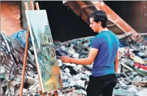  ?? XINHUA ?? An artist paints in the Yarmuk refugee camp on the southern outskirts of Damascus, Syria, on Sunday. The camp is now largely abandoned after seven years of civil war.