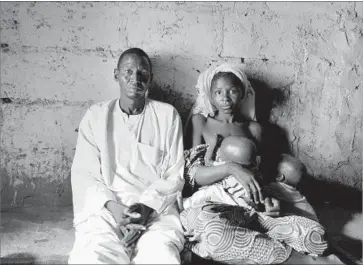  ?? Photograph­s by Robyn Dixon Los Angeles Times ?? “I FEEL empty, knowing that I’m helpless,” says Saleh Umar, who fears that his youngest son, Hassan, will die. “Here I am, poor, without work, without money to take care of him.” Wife Hadiza Adamu holds their twins.