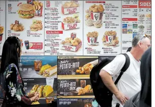  ?? AP/BEBETO MATTHEWS ?? Diners check a menu recently at a KFC in New York that displays calorie counts of menu items. The Trump administra­tion is proceeding with requiremen­ts that restaurant chains, convenienc­e stores, pizza delivery chains and movie theaters post calorie...