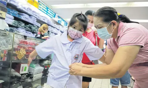  ?? POOMLARD SOMCHAI ?? A girl is helped to try on a school uniform at a store near Paknam market in Samut Prakan yesterday. Most schools are opening for the new term on May 17.