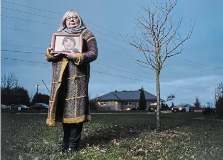  ?? M AT H E W MCCARTHY WATERLOO REGION RECORD ?? Judie Moore holds a photograph of her son, Lucas Shortreed, next to a tree planted in his memory in Fergus.