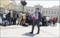  ?? THANASSIS STAVRAKIS / ASSOCIATED PRESS ?? A pedestrian passes a food handout line Tuesday outside the headquarte­rs of the National Bank of Greece in Athens. The country’s government reached a deal with its creditors that will allow it to avoid bankruptcy.