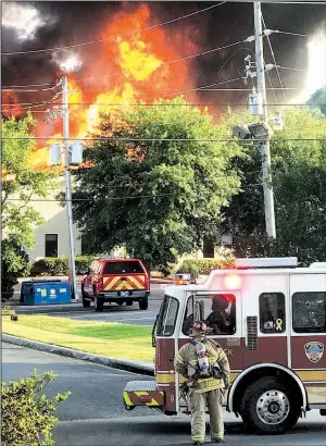  ?? Arkansas Democrat-Gazette/JENNIFER CHRISTMAN ?? A Little Rock firefighte­r watches as flames dance high above the roof of 3 Office Park Dr. on Sunday evening. The fire destroyed the building, which housed three tenants.