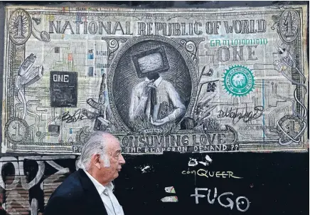  ?? Photo: REUTERS ?? A man walks past a graffiti illustrati­ng a modified banknote in Athens this week, as Greek banks are close to collapse.