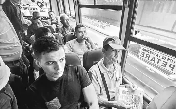  ??  ?? A group of people on a bus watch a presentati­on by reporters involved in the Bus TV news initiative.