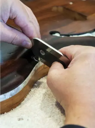  ??  ?? Left: Scraping the binding to take off stain before final glossingBe­low: Louis Panormo’s guitar logo above the Solace Instrument­s logo