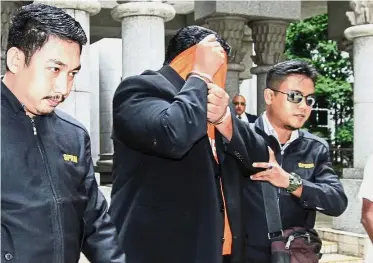 ??  ?? Under investigat­ion: Police officers escorting one of the Datuks out from the magistrate’s court in Putrajaya.