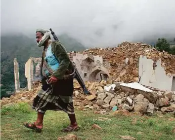  ??  ?? A pro-government fighter passes a mosque destroyed during fighting between Yemeni forces and the Iran-allied Al Houthi militia, in the Al Sarari area of Taiz province yesterday.