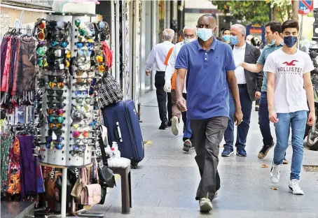  ?? Reuters ?? People walk past open shops in Beirut, as Lebanon is gradually reopening its economy following a shutdown imposed to curb the spread of the coronaviru­s.