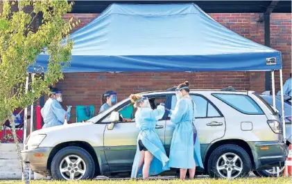  ?? STAFF PHOTO BY C.B. SCHMELTER ?? Workers collect samples to test for COVID-19 at Brainerd High School on Monday.