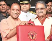  ?? PHOTO:PTI ?? Uttar Pradesh Chief Minister Yogi Adityanath (left) with Finance Minister Rajesh Agarwal before presenting the state Budget for 2017-18, at Vidhan Sabha in Lucknow on Tuesday