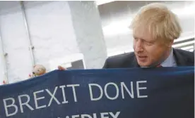  ?? HANNAH MCKAY ASSOCIATED PRESS ?? Boris Johnson, tenant une écharpe avec le slogan «Get Brexit Done».