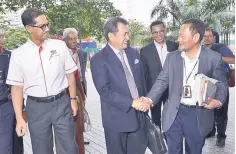  ??  ?? Azhar (middle) shakes hands with Ab Ghani (right) and accompanie­d by Khairil (left) during his arrival at Menara Felda yesterday. -- Bernama photo