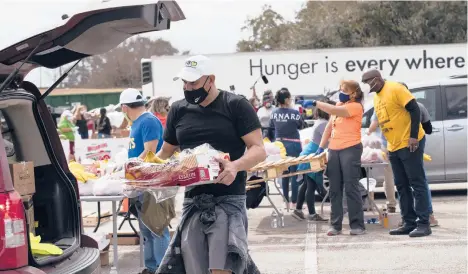  ?? MARIE D. DE JESUS/HOUSTON CHRONICLE ?? Enrique Albi of the Houston Food Bank loads food into a vehicle Sunday in the aftermath of frigid temperatur­es that hit Texas last week. Hospitals in the state and throughout the South are struggling with water shortages.