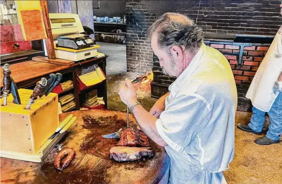  ?? Photos by J.C. Reid/contributo­r ?? The meat cutter does his work at the cutting block at Smitty’s Market in Lockhart. Here, the reality lives up to the myth and legends of Texas barbecue.