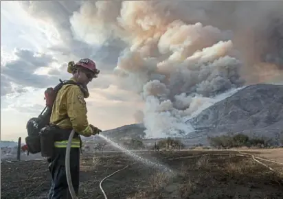  ??  ?? A firefighte­r works on hot spots Saturday in the foothills of Yucaipa, east of Los Angeles. Wildfires prompted evacuation orders for eastern portions of the city of 54,000 along with several mountain communitie­s. Ringo H. W. Chiu/ Associated Press