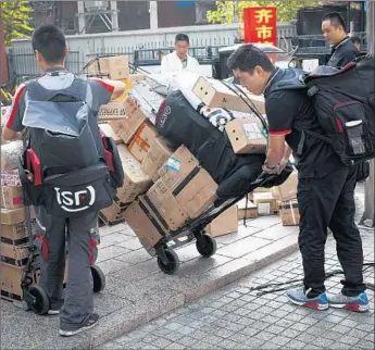  ?? Andy Wong Associated Press ?? DELIVERY WORKERS pull carts loaded with goods for their customers outside an office building in Beijing on Monday. China vows retaliatio­n if President Trump escalates the tariff battle.