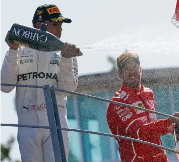  ?? Foto: dpa ?? Einen guten Grund zu feiern hatte Formel 1 Fahrer Lewis Hamilton (links) in Monza: Mit seinem Sieg löst er Sebastian Vettel an der Spitze der Fahrerwert­ung ab.