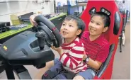  ??  ?? PUTTING HIS FOOT DOWN: Brothers, Adam, 4, left, and Daniel Ah Sing, 9, take a fun ride in one of the two super cool virtual racing car simulators that will be provided by Anstek Computers in their IT Café PICTURE: www.impactphot­ography.co.za