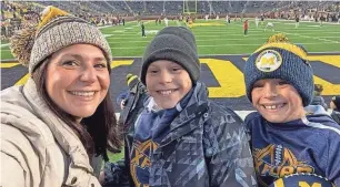  ?? PROVIDED BY ROSA EVERITT ?? Rosa Everitt, an assistant principal at Lake Orion High School, is seen with her sons Lucas and Aidan, right, at a University of Michigan football game on Nov. 6. The boys attend Oxford Elementary. Everitt said Abby Maisel’s artwork “shows how we all feel.”