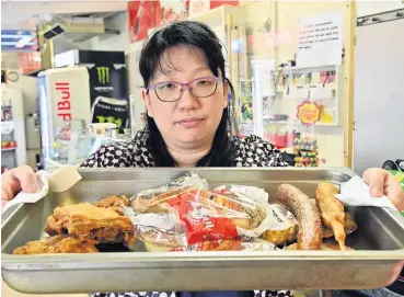  ?? PHOTO: LINDA ROBERTSON ?? What a waste . . . East Taieri Dairy and Takeaways owner Crystal Cao with a tray of food, typical of what she has had to throw away because of continuing unplanned power cuts in the area.