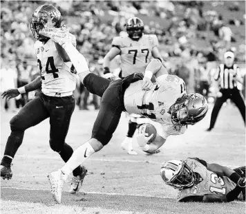  ?? STEPHEN M. DOWELL/ORLANDO SENTINEL ?? UCF’s Dillon Gabriel leaps into the end zone for a dramatic touchdown over Marshall safety Nazeeh Johnson (13) during the Gasparilla Bowl on Monday in Tampa. Gabriel was named the game’s MVP after passing for 260 yards and two TDs.