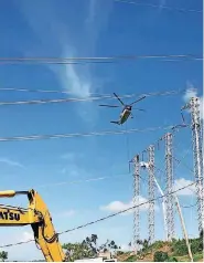  ??  ?? A helicopter carries a line to a power pole in Puerto Rico, recently. Helicopter­s are being used there to help ground crews string line, set poles and to control vegetation near power transmissi­on and distributi­on systems.