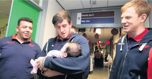  ?? Picture: Ian Williams/ Riley Sports Photograph­y ?? Scarlets players Javan Sebastian, Dan Jones (with baby) and Rhys Patchell during their visit to Cilgerran children’s ward.