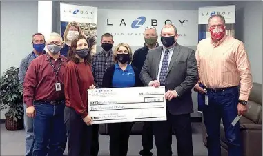  ?? (Courtesy Photo) ?? La-Z-B oy presents a $5,000 check to Bright Futures Siloam Springs on Friday to help replenish the supplies lost to water damage from flooding caused by burst pipes during the unusually cold weather in February. Pictured are (front left) Tiffany Hansen, Bright Futures coordinato­r; Audra Farrell, La-Z-Boy human resources manager; Jody Wiggins, school superinten­dent; Daren Davison, La-ZBoy general manager; (back left) Dean Graham, La-Z-Boy controller; Matt Bevis, La-Z-Boy CI and facilities manager; Cathy Simkins, La-Z-Boy supply chain manager; Jim Larson, La-Z-Boy EHS manager; and Mike Wilmon, La-Z-Boy production manager.