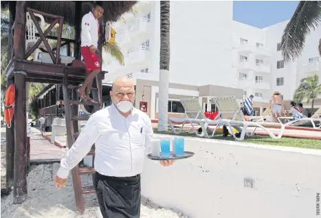  ??  ?? A waiter wears a protective mask at a hotel after local authoritie­s imposed strict sanitary measures to gradually reopen despite the coronaviru­s pandemic in Cancun, Mexico June 10.