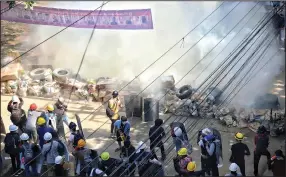  ?? (AP) ?? Defiant Burmese protesters behind a barricade face tear gas deployed by security forces Friday in San Chaung township.