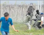  ??  ?? DETERMINED: Migrants try to remove barbed wire.