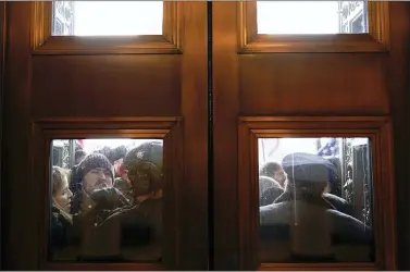  ?? ANDREW HARNIK — THE ASSOCIATED PRESS FILE ?? In this Jan 6, 2021, file photo, U.S. Capitol Police try to hold back rioters outside the east doors to the House side of the U.S. Capitol. The volume of people inside the Capitol building, along with the lack of arrests made at the time of the riot, has made it difficult to identify people, even with the glut of social media evidence. Federal agents have dug through thousands of social media posts, used sweeping warrants to obtain informatio­n on cellphones in the area of the Capitol, facial recognitio­n tools and logs of devices that logged into the congressio­nal WiFi during the riot to try to identify the hundreds of people who stormed the Capitol.