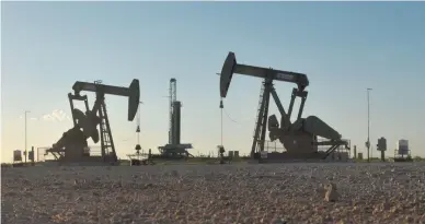  ?? REUTERS ?? PUMP JACKS operate in front of a drilling rig in an oil field in Midland, Texas, US, Aug. 22, 2018.