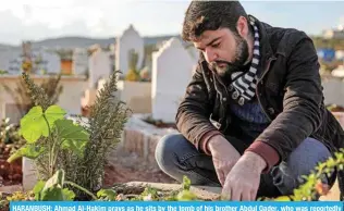  ?? ?? HARANBUSH: Ahmad Al-Hakim prays as he sits by the tomb of his brother Abdul Qader, who was reportedly killed by torture while in captivity by Hayat Tahrir Al-Sham. — AFP photos