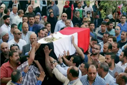  ?? ALAA ELKASSAS — THE ASSOCIATED PRESS ?? People carry the coffin, covered with the an Egyptian flag, of police Capt. Ahmed Fayez, who was killed in a gunbattle in al-Wahat al-Bahriya area in Giza province, about 84 miles southwest of Cairo, during his funeral at Al-Hosary mosque, in Cairo on...