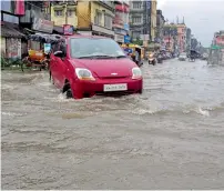  ?? PTI ?? A car wades through a flooded street after heavy downpour in Silchar, Assam, on Thursday. —