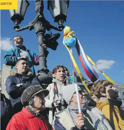  ?? ANDREW LUBIMOV / THE ASSOCIATED PRESS ?? A demonstrat­or holds up a yellow duck in Moscow on Sunday, just one instance worldwide where protesters have co-opted the toy.