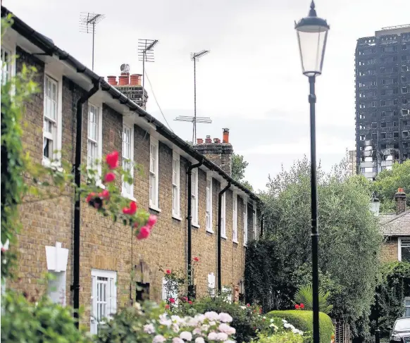  ??  ?? > The remains of Grenfell Tower are seen behind a Victorian terrace in London