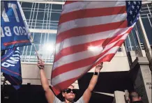  ?? Spencer Platt / Getty Images ?? A Donald Trump supporter waves flags outside the Philadelph­ia Convention Center as the counting of ballots continued in the state on Nov. 6. Joe Biden took the lead in the vote count in Pennsylvan­ia on Friday morning from President Trump.