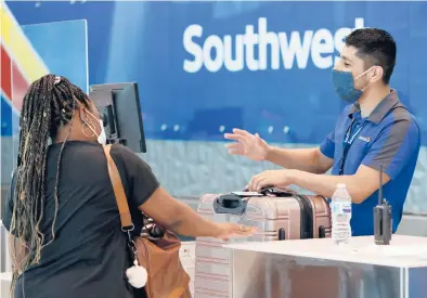  ?? TONY GUTIERREZ/AP ?? Southwest Airlines employee Oscar Gonzalez assists a passenger at the ticket counter at Love Field in Dallas.