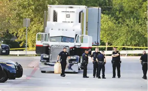  ?? AP ?? San Antonio police officers investigat­e the scene yesterday, where eight people were found dead in a tractor-trailer loaded with at least 30 others outside a Walmart store in stifling summer heat in what police are calling a horrific human traffickin­g...