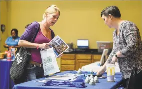  ?? Chris Dorst / Associated Press ?? A woman picks up informatio­n about a prospectiv­e employer at a job fair.